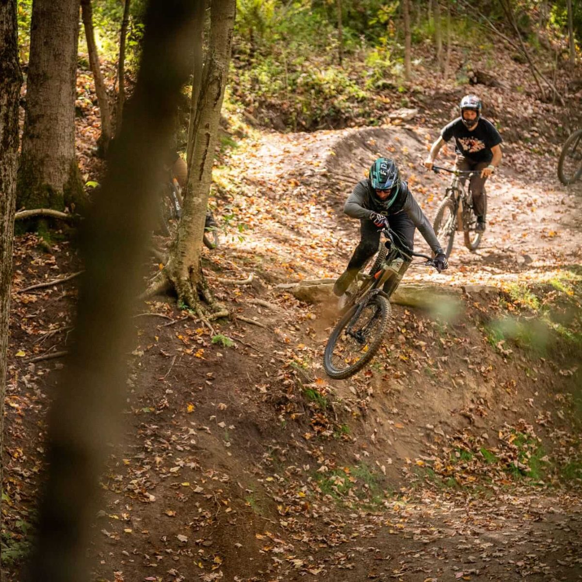 Three bikers riding rugged dirt terrain at HoliMont Bike Park